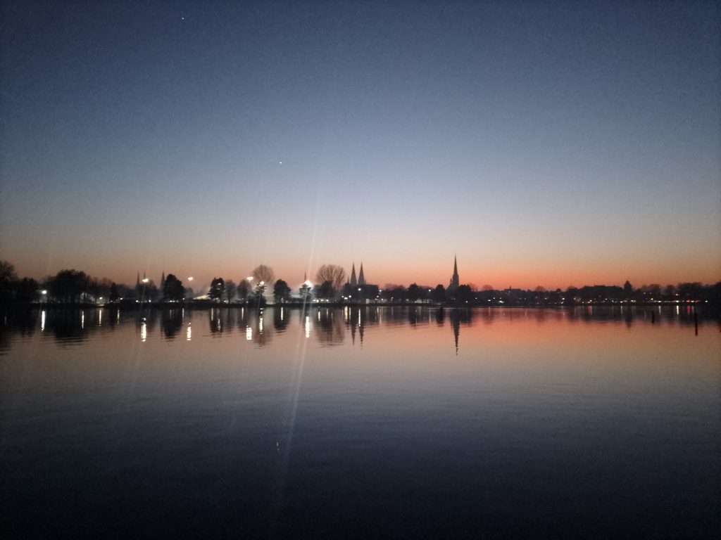 Die Lübecker Altstadt beim Sonnenuntergang von der Ostseite des Lübecker Kanals aus fotografiert. Kostenlos mit Quellenangabe nutzbar.